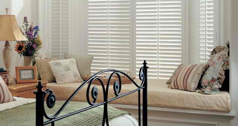 White shutters in a modern bedroom bay window.